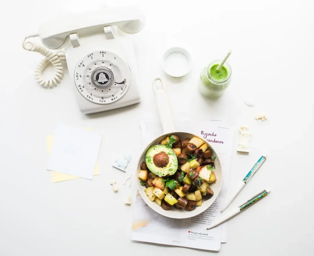Healthy meal in a bowl along with a telephone and a smoothie alongside