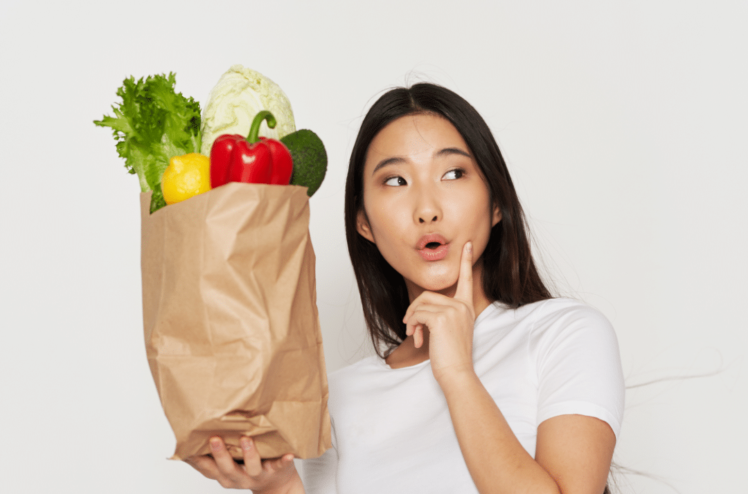 Girl carrying paper bag full of vegetables